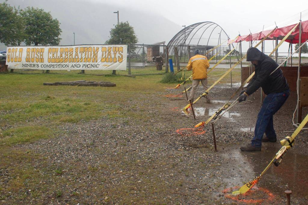 Gabe Holst, foreground, a Coeur Alaska Inc. mining intern from Springfield, Missouri, tightens an anchor rope on a shelter tent at Savikko Field on Monday where vendors will be during Juneau Gold Rush Days. (Mark Sabbatini / Juneau Empire)