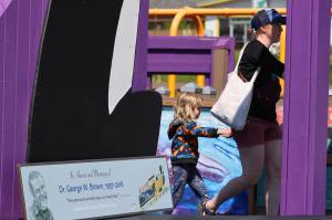 Hali Hall, 4, holds Heidi Hall's hand Saturday afternoon as they walk past a sign honoring to Dr. George Brown at Project Playground. Ben Brown, son of the longtime children's advocate, said during a short dedication ceremony that he was pleased to see the park being enjoyed by children. (Ben Hohenstatt / Juneau Empire)