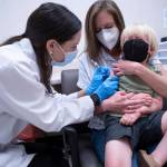 Pharmacist Kaitlin Harring, left, administers a Moderna COVID-19 vaccination to three year-old Fletcher Pack, while he sits on the lap of his mother, McKenzie Pack, at Walgreens pharmacy Monday, June 20, 2022, in Lexington, S.C. Today marked the first day COVID-19 vaccinations were made available to children under 5 in the United States. (AP Photo/Sean Rayford)