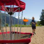Pioneers of Alaska member Ricky Deising lands a hole-in-one as he tries frisbee golf for the first time on Sandy Beach, Douglas.(Clarise Larson / Juneau Empire)