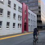A man bikes past the Assembly Building, located just across the street from the Alaska State Capitol. The building is set to be renovated into a 33-unit multi-family apartment complex to house legislative staff. (Clarise Larson /Juneau Empire)