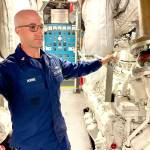 The U.S. Coast Guard Cutter Reef Shark engineering petty officer Chief Petty Officer Anthony Horine points out the cutters dual engines in the engineering spaces.