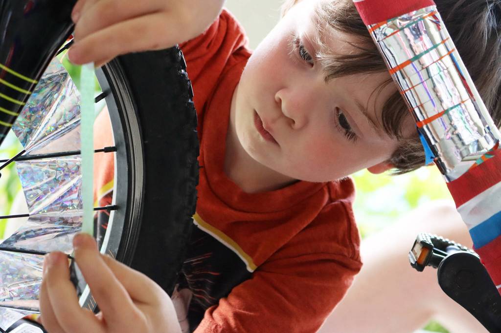 Kingston Wilson, 7, applies reflective decorations to a bike on July 3, 2021. Dozens of youths showed up to decorate their bikes. (Ben Hohenstatt / Juneau Empire)