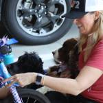 Holly Johnson, with help from dogs Hazel and Stella, decorates a bike during the Douglas Fourth of July Committees annual Bicycle Decorating session held at the Douglas Public Library on July 2, 2022. (Michael S. Lockett / Juneau Empire)