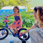 Sayler Williams, left, poses with her freshly decorated bike as Abby Williams looks on during the Douglas Fourth of July Committees annual Bicycle Decorating session held at the Douglas Public Library on July 2, 2022. (Michael S. Lockett / Juneau Empire)