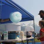 Mia Halloway, 6, grabs a cotton candy with her dad in Savikko Park. A long string of kids stood in line to grab a cotton candy from the Twhrly Whrliy Cotton Candy stand on a bright and sunny Fourth of July afternoon. (Clarise Larson / Juneau Empire)