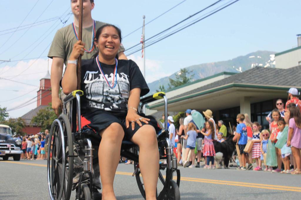 A parade participant holds a patriotic flag as she makes her way down the street. (Clarise Larson / Juneau Empire)