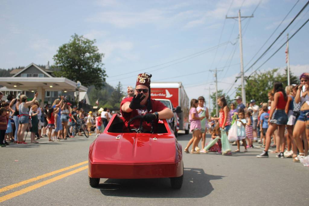 A Juneau-Douglas Shrine Club member rides in a serpentine pattern as kids chase him for candy. (Clarise Larson / Juneau Empire)