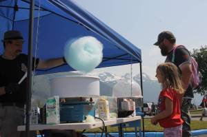 Mia Halloway (6) grabs a cotton candy with her dad in Savikko Park. A long string of kids stood in line to grab a cotton candy from the Twhrly Whrliy Cotton Candy stand on a bright and sunny Fourth of July afternoon. (Clarise Larson / Juneau Empire)