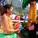 Rachel Hurst hands her son Benjamin, 4, a beach ball to throw to the crowd from the Hawaiian-themed Juneau Urgent Care float during the July 4 parade in downtown Juneau. (Mark Sabbatini / Juneau Empire)