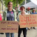 Constance and Robin Miles holding signs expressing opinions at Planned Parenthood rally. (Jonson Kuhn / Juneau Empire)