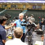 Media members exchange photos of themselves while setting up on the riser located at the far end of the floor from the rally stage at the Alaska Airlines Center. (Mark Sabbatini / Juneau Empire)
