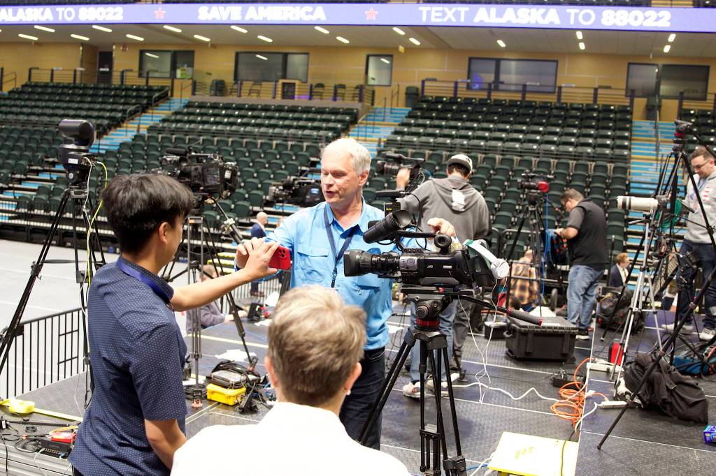 Media members exchange photos of themselves while setting up on the riser located at the far end of the floor from the rally stage at the Alaska Airlines Center. (Mark Sabbatini / Juneau Empire)
