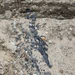 Tarry residue can be seen on the riverbank of the Eagle River as erosion exposes more debris from roadbuilding infrastructure buried decades. (Michael S. Lockett / Juneau Empire)