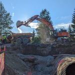An excavator dumps dirt into a dump truck as crews perform work near Mendenhall Loop Road on Friday, July 15, 2022. (Courtesy photo / Sam Dapcevich)