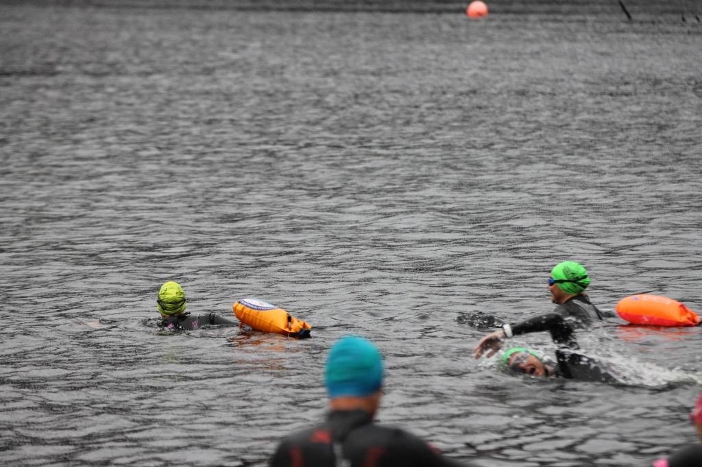 The team begins their hour-long group swim workout at Auke lake. (Clarise Larson / Juneau Empire)