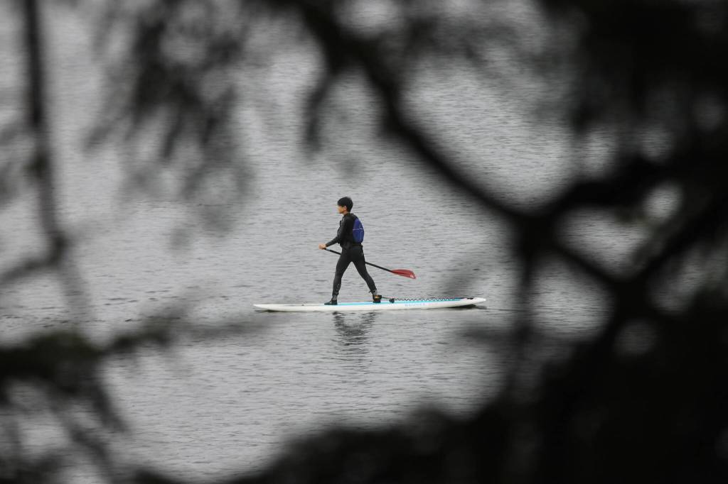 A partner of an athlete follows the team on a paddle board to ensure everyones safety during the workout. (Clarise Larson / Juneau Empire)