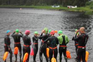 The High Cadence Ironman team begins their hour-long group swim workout at Auke lake. (Clarise Larson / Juneau Empire)
