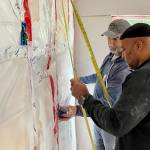Chris Cotton, in black, and Matthew Wetherholt measure off distance in a house they and other members of Team Rubicon, a disaster-recovery nonprofit, are helping to restore following the Haines landslide of 2020. (Michael S. Lockett / Juneau Empire)