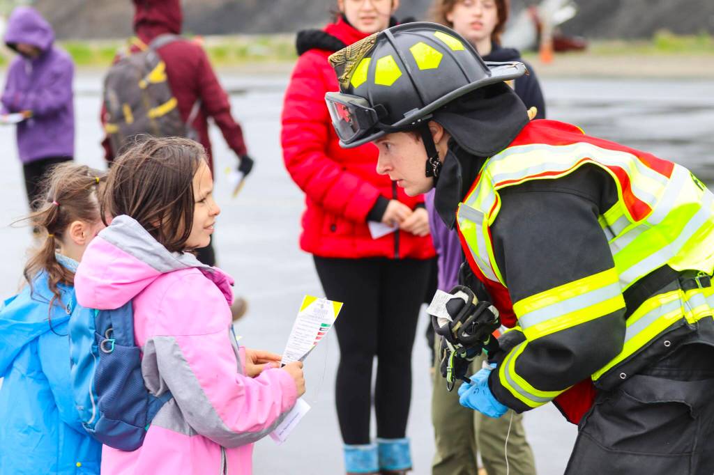 A Capital City Fire/Rescue firefighter talks to kids acting as casualties during an exercise simulating a plane crash at Juneau International Airport on July 23, 2022. (Michael S. Lockett / Juneau Empire)