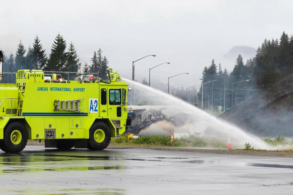 A Capital City Fire/Rescue engine soaks down a fire as part of an exercising simulating a plane crash at Juneau International Airport on July 23, 2022. (Michael S. Lockett / Juneau Empire)