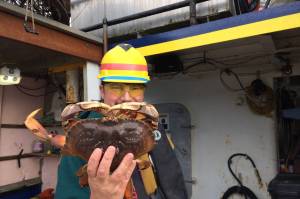 A fisherman holds a Dungeness crab caught during the 2021 season. (Courtesy Photo/ Joseph Stratman, Alaska Department of Fish and Game)