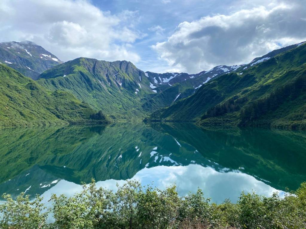 Blue sky, clouds and mountains are reflected in the Salmon Creek Reservoir on Aug. 20, 2022. (Courtesy Photo / Denise Carroll)