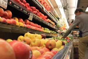 A shopper reaches for some fruit in the produce section at Super Bear IGA. City and Borough of Juneau members OKd an ordinance that approves funding for a third party to survey Juneau residents on whether the city should remove the sales tax on unprepared food  and how it should make up for the potential lost revenue. (Clarise Larson / Juneau Empire)