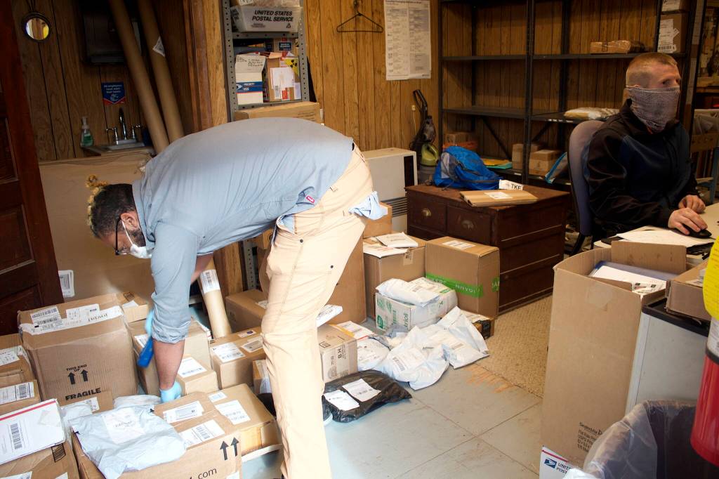 J.T. Collins, left, and Flint Allred sort through the backlog of mail at the Tenakee Springs post office that accumulated as of Monday morning when the post office was closed for more than a week due to their absence and the departure of a third employee at the post office. (Mark Sabbatini / Juneau Empire)