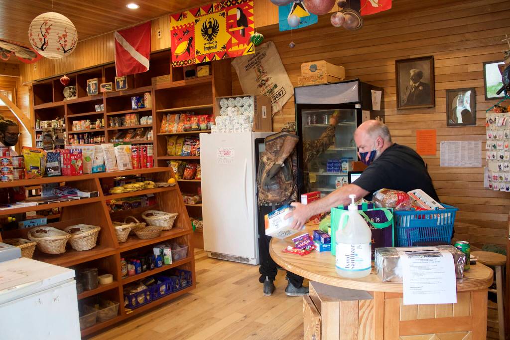 Ken Merrill, owner of Tenakee Springs Market, rings up purchases Monday at the towns only source for groceries and other supplies. He bought the store in 2013, but said these days its more of a community service than profit-making venture due to struggles getting supplies and the desire to keep goods affordable for the towns shrinking population. (Mark Sabbatini / Juneau Empire)