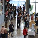 Athletes and race supporters walk the foyer of Thunder Mountain High School to visit the various Ironman and local booths open at the Ironman Village. (Ben Hohenstatt / Juneau Empire)