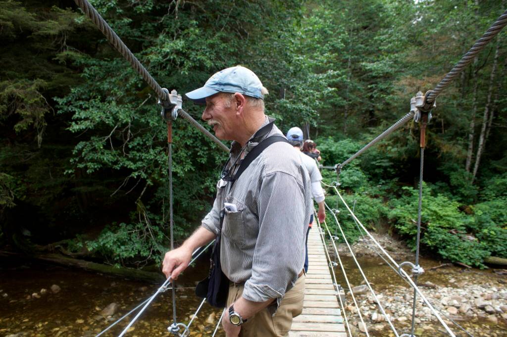 Tenakee Springs Mayor Dan Kennedy looks for salmon in a creek at the edge of town from a bridge that was washed away during a storm in December of 2020 that caused extensive flooding damage throughout the community. In addition to ongoing efforts trying to get disaster relief funds from state and federal officials, Kennedy was among those laboring to rebuild the bridge and numerous other recovery projects. (Mark Sabbatini / Juneau Empire)