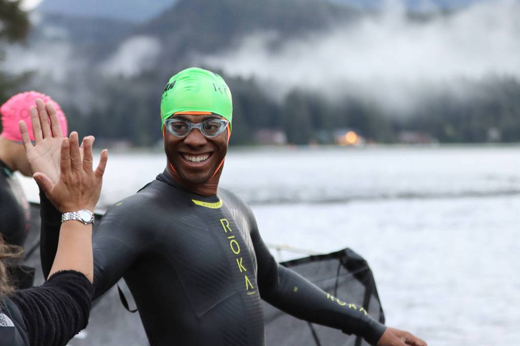 Phillip McIver smiles after getting a high-five ahead of the swimming portion of Ironman Alaska. (Ben Hohenstatt / Juneau Empire)