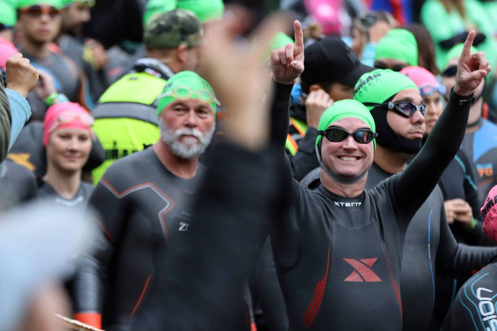 Athletes respond to cheers from spectators before entering the 56-degree water of Auke Lake during Ironman Alaska. The water temperature was the coldest recorded all week, according to an announcement made dring the race, and caused the swimming portion of the event to be cut to 1.2 miles instead of the planned 2.4 miles. (Ben Hohenstatt / Juneau Empire)