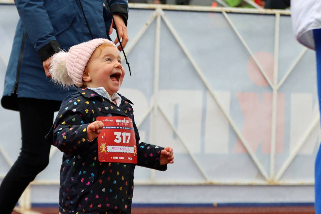 Adaline Kot, 2, of Juneau beams after high-fiving UAS mascot Spike Saturday at Thunder Mountain High School. (Ben Hohenstatt / Juneau Empire)