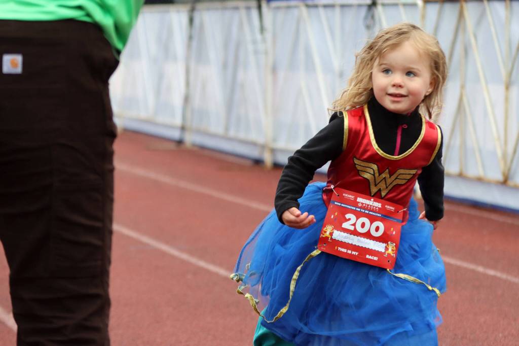 Audrey Quinn Pilcher, 3, looks up at a volunteer during Saturdays Ironkids Alaska Fun Run event. (Ben Hohenstatt / Juneau Empire)