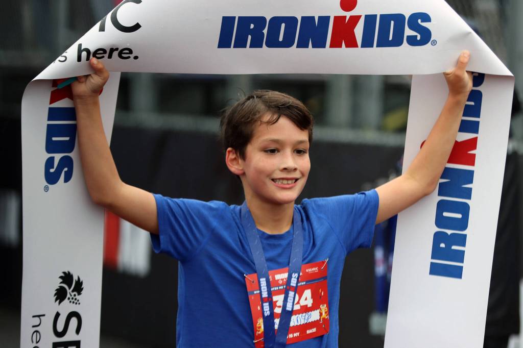Austin Treston, 9, of Juneau holds up an Ironkids banner after finishing a 1-mile run. Treston finished his fun run in first place. (Ben Hohenstatt / Juneau Empire)