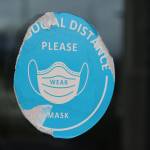 This late-April photo shows a damaged sticker on a door at Thunder Mountain High School reminding people to social distance and wear masks inside the building. Masks will not be required in school buildings this year. (Ben Hohenstatt / Juneau Empire File)