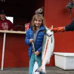 Grace Frederick stands in front of the Amalga Harbor weigh in station next to her 11.8-pound coho salmon she caught with the help of her father, Brian. (Clarise Larson / Juneau Empire)