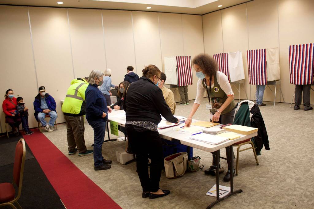 Emily Kane, precinct chair at the Elizabeth Peratrovich Hall polling station, instructs a voter on filling out the ballot for Tuesdays combined special and primary election. Kane, a local election worker since 2016, said there is a high rate of spoiled ballots this year due to confusion about the new ranked choice voting system. (Mark Sabbatini / Juneau Empire)