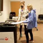 Hanna Stickel, a precinct co-chair at the State Of Alaska Library Archives Museum polling site, helps a voter insert a ballot into a Dominion counting machine Tuesday evening. Election workers said there were no complaints from voters about the machines that some election integrity skeptics have questioned. But the state’s new ranked choice voting meant the machine did pause processing numerous ballots because people ranked the same candidate as their preference in every box. (Mark Sabbatini / Juneau Empire)