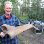 A gold miner holds a woolly mammoth femur he found as he worked frozen ground in the Fortymile River mining district. (Courtesy Photo / Ned Rozell)