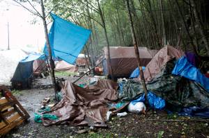 Trash, debris and abandoned belongings are strewn among occupied tents at the Mill Campground on the mountainside across from the cargo ship terminal in downtown Juneau on Monday. The campsite has been at or beyond full capacity through the summer, as have other facilities for the homeless, due to various problems including skyrocketing housing costs and lack of vacancies even for people able to pay at least some rent. (Mark Sabbatini / Juneau Empire)