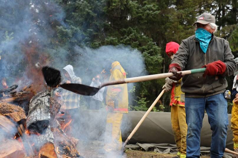 Clarise Larson / Juneau Empire 
Wayne Price chucks a piece of burn wood onto the fire as he and student dug through it in search of lava rocks. The rocks do not originate from Angoon and Price brought them over for this specific reason.
Wayne Price chucks a piece of burn wood onto the fire as he and student dug through it in search of lava rocks. The rocks do not originate from Angoon and Price brought them over for this specific reason. (Clarise Larson / Juneau Empire)