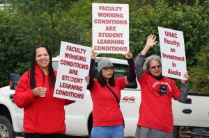 UNAC supporters Angel Collins, JoMarie Alba and Lisa Hoferkamp hold signs Thursday morning in the middle of a Glacier Highway roundabout near the University of Alaska Southeast campus in Juneau. The University of Alaska Board of Regents began a two-day meeting at UAS on Thursday. University of Alaska and the faculty union have not come to an agreement after over a year of negotiations. (Ben Hohenstatt / Juneau Empire)