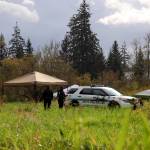 Clarise Larson / Juneau Empire 
On Thursday morning at what police described as an active crime scene, JPD Officer Austin Thomas and Officer Taylor Davis walk the fielded area which was blocked off by crime scene tape. Multiple tents and a police vehicle sat in the field where the tape surrounded, another police vehicle sat in a dirt parking area.