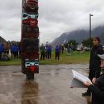 Kitty Eddy, a longtime Tlingit language education leader in Juneau, offers a welcoming message to about 250 cross-country competitors and coaches from Southeast Alaska high schools at the totem pole at A Káx Yaa Andagan Yé (Sandy Beach) before the Capital City Invite on Saturday morning. (Mark Sabbatini / Juneau Empire)