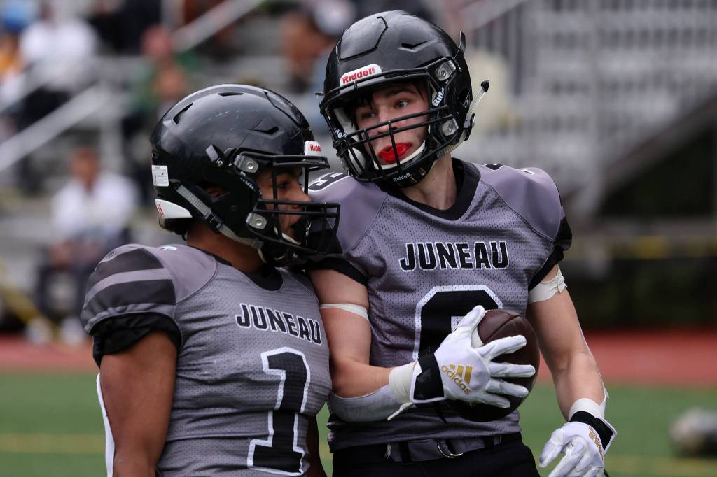 Jarrell Williams (1) talks to Payton Grant (9) during a 49-32 win against Service High School. The seniors had big games against the Cougars. Williams rushed for two touchdowns and threw for a score  all in the first quarter. Grant also rushed for a score and broke up passes in key moments on defense. (Ben Hohenstatt / Juneau Empire)