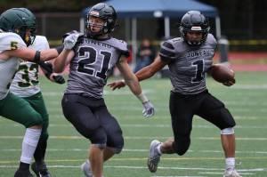 A Lucas White (21) block buys Jarrell Williams (1) more room to work during a 49-32 win against Service High School. (Ben Hohenstatt / Juneau Empire)