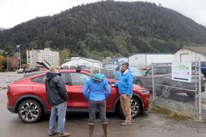 Jim Scheufelt, right, explains how his newly purchased Ford Mustang Mach-E operates to a couple of visitors at the ninth annual Juneau EV EBIKE Roundup on Saturday. He said he has always driven Fords because his father worked for the company, but decided this year to make the switch from gas to electric. He said his wife drives a similar model and their son an electric Ford Focus, making them an all-EV household. (Mark Sabbatini / Juneau Empire)